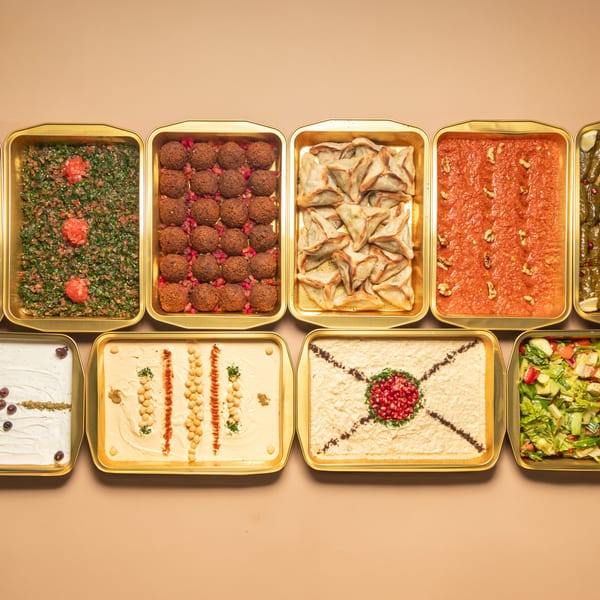 Top-down view of golden trays filled with various Lebanese dishes like tabbouleh, falafel, and hummus.